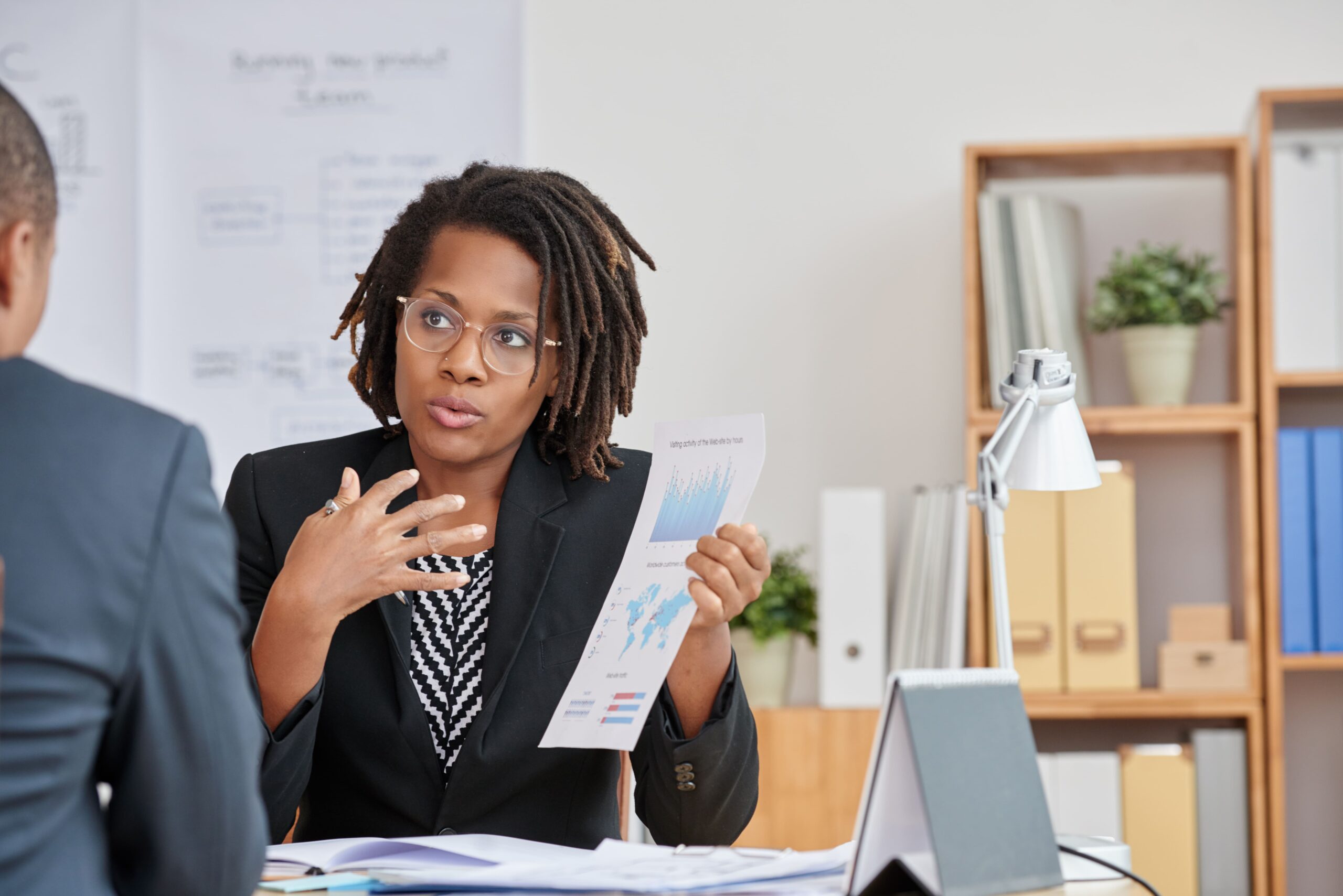 portrait attractive cuban woman presenting statistical information her unrecognizable boss